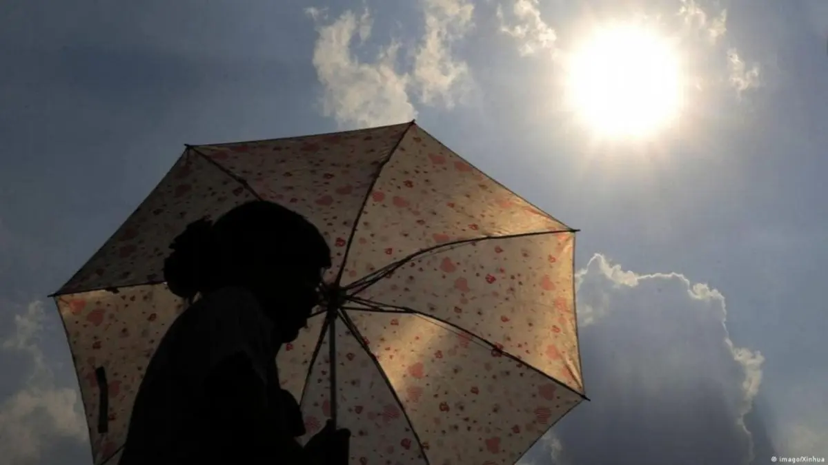 Mujer con sombrilla bajo el sol. / Foto de archivo