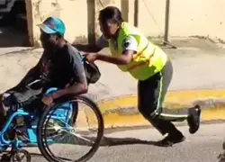 Agente de la Digesett es captada ayudando a hombre en silla de ruedas en Haina