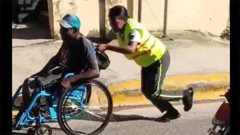 Agente de la Digesett es captada ayudando a hombre en silla de ruedas en Haina