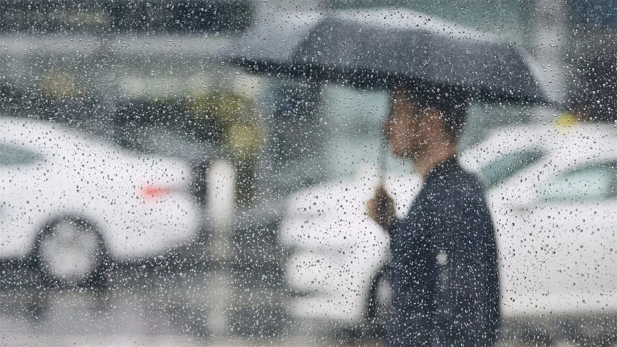 Hombre sosteniendo un paraguas bajo la lluvia.