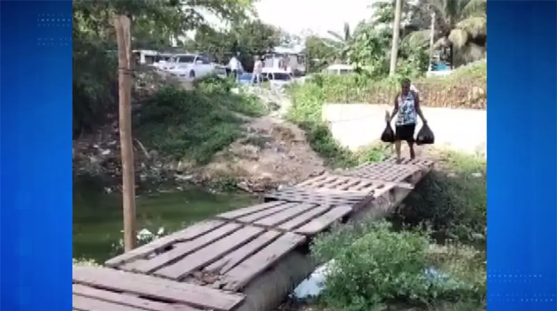 Improvisan puente con ramas y tablas para cruzar una cañada