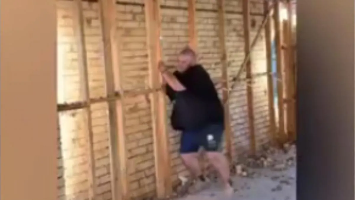 Un hombre derriba una pared de ladrillo de un empujón