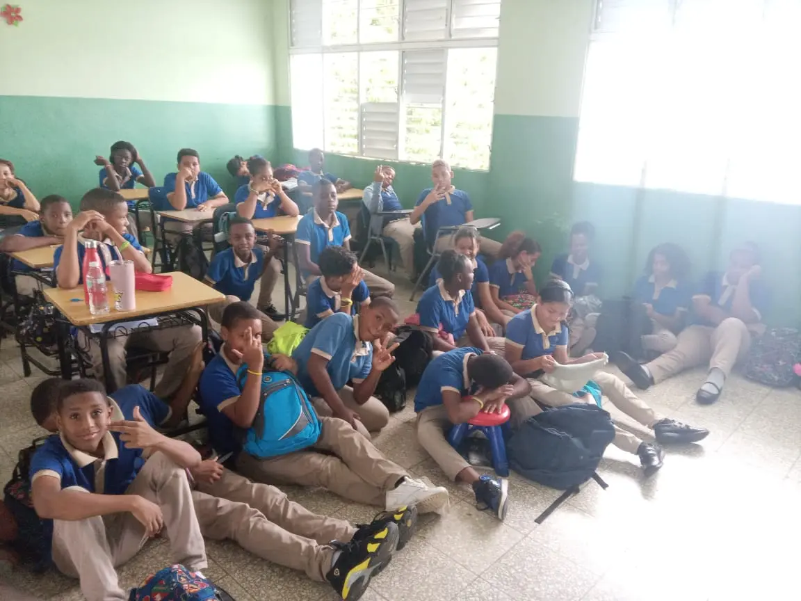 Estudiantes toman clases en el piso por falta butacas