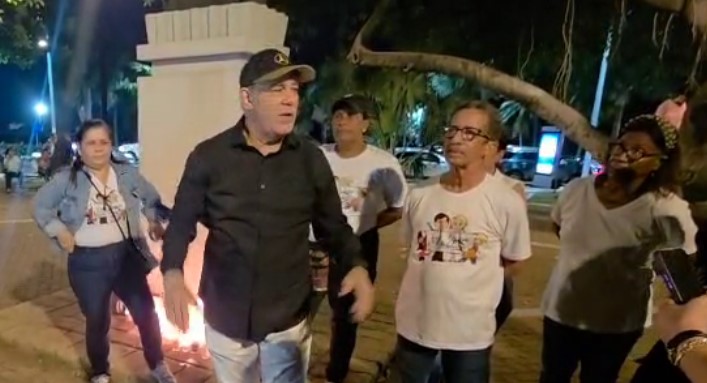 Grupo de personas hablando en parque nocturno.