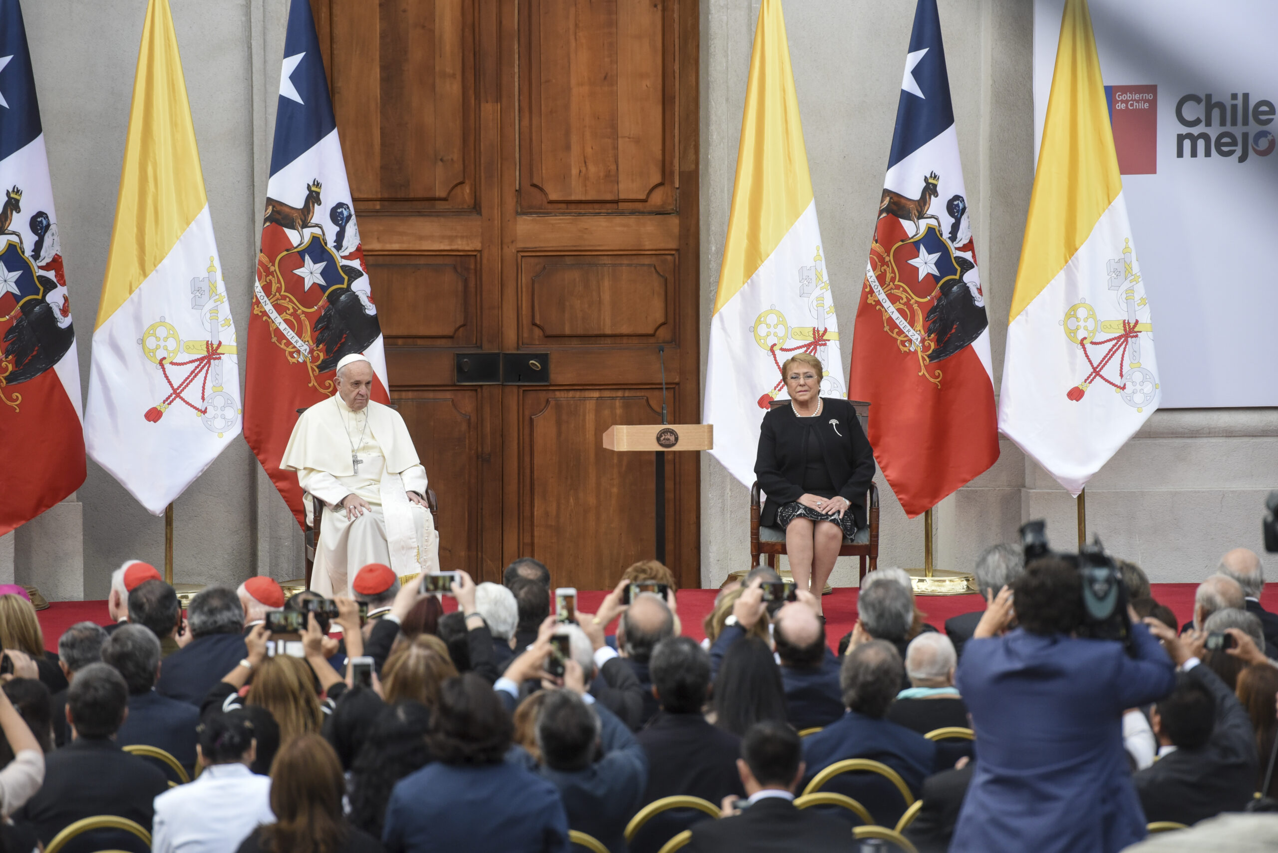 Líderes en evento con banderas chilenas y vaticanas.