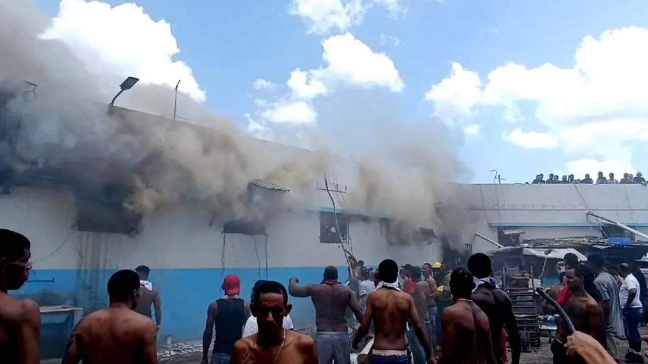 Personas observan humo en edificio en llamas.