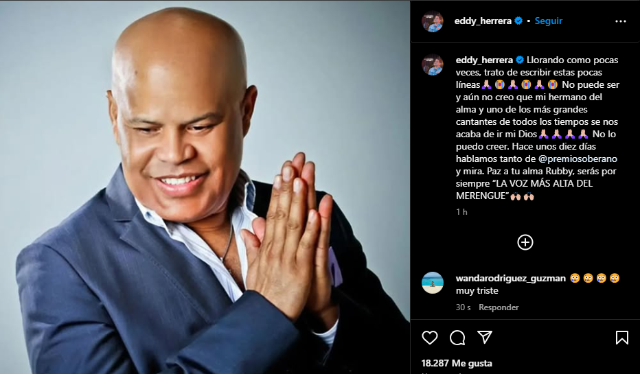 Hombre sonriente con manos juntas y traje formal.