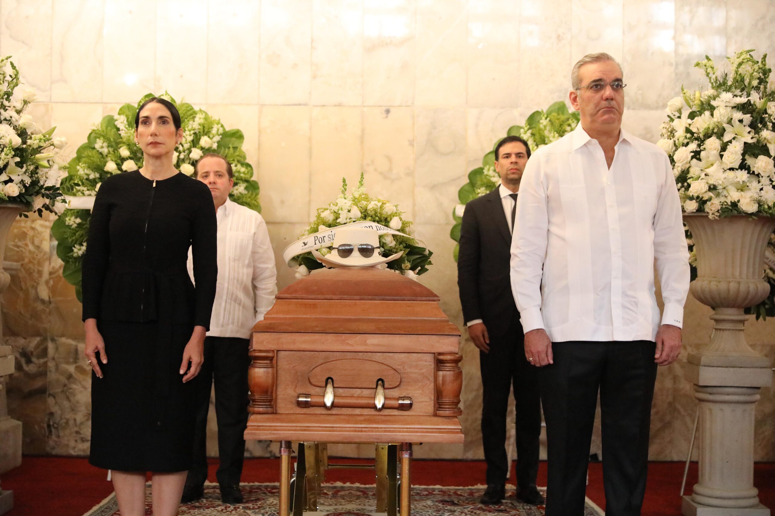 Personas en funeral con ataúd y flores