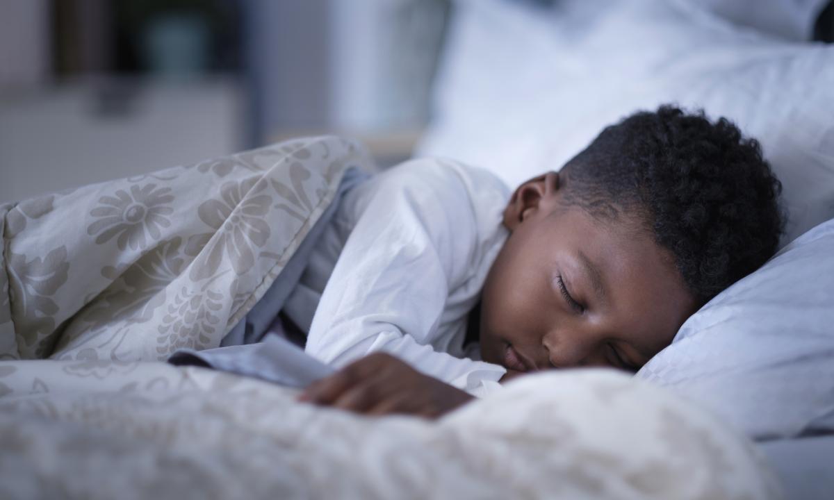 Niño durmiendo plácidamente en cama con edredón floral.