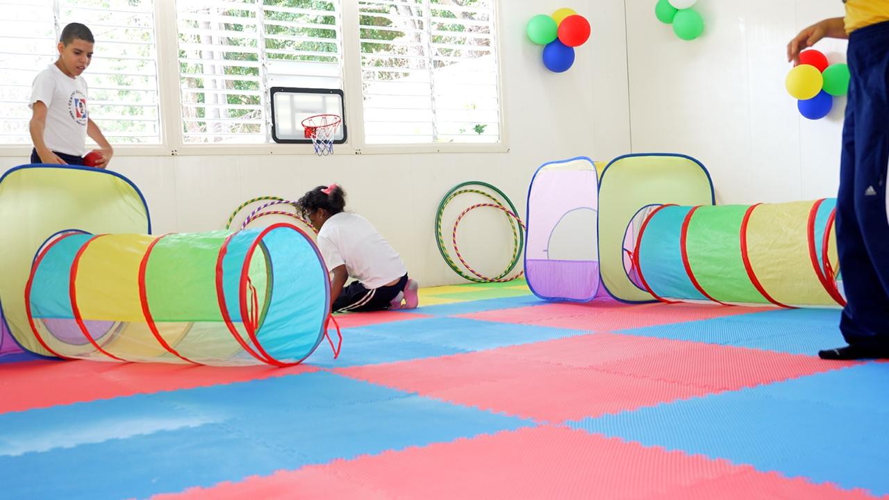 Niños jugando en guardería con túneles de colores.
