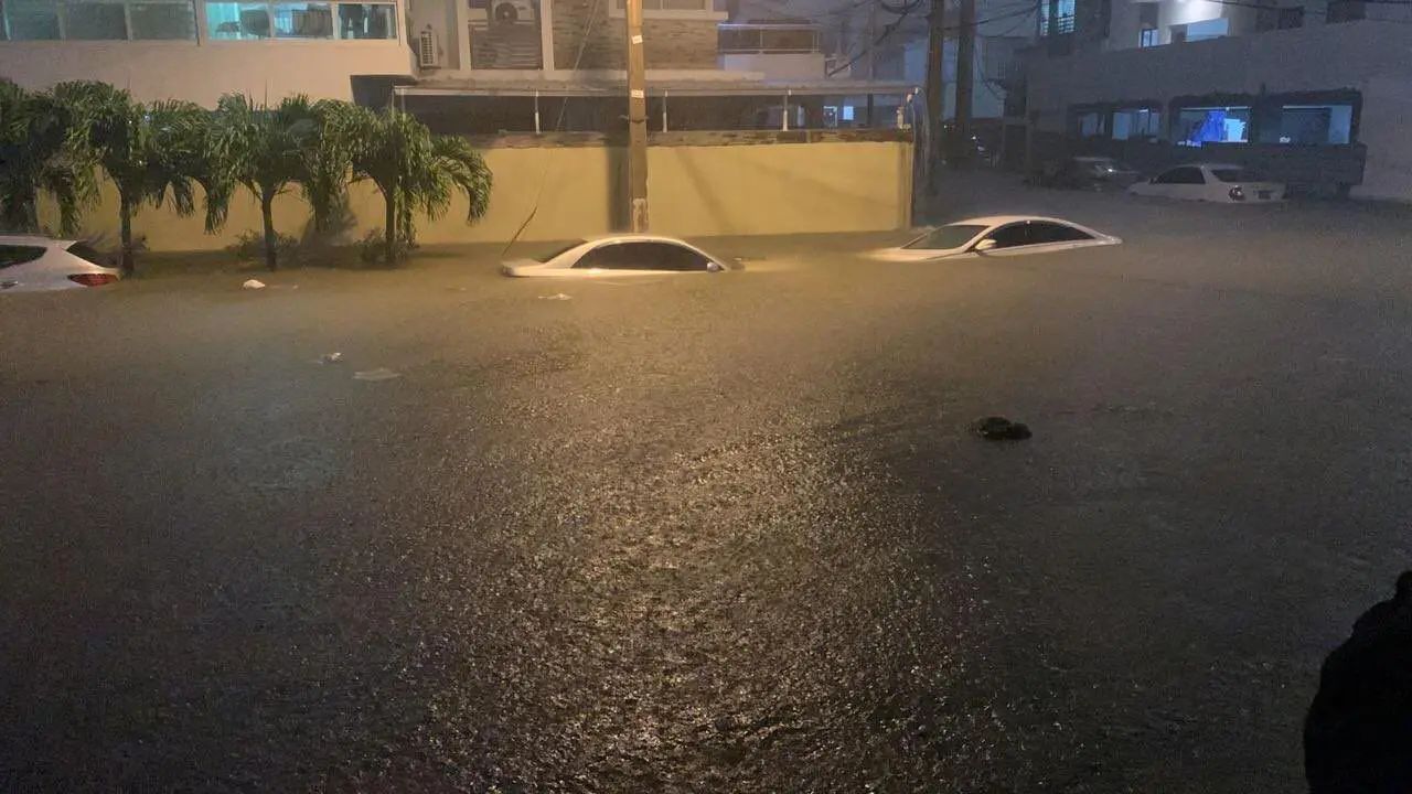 Coches sumergidos en una calle inundada de noche.