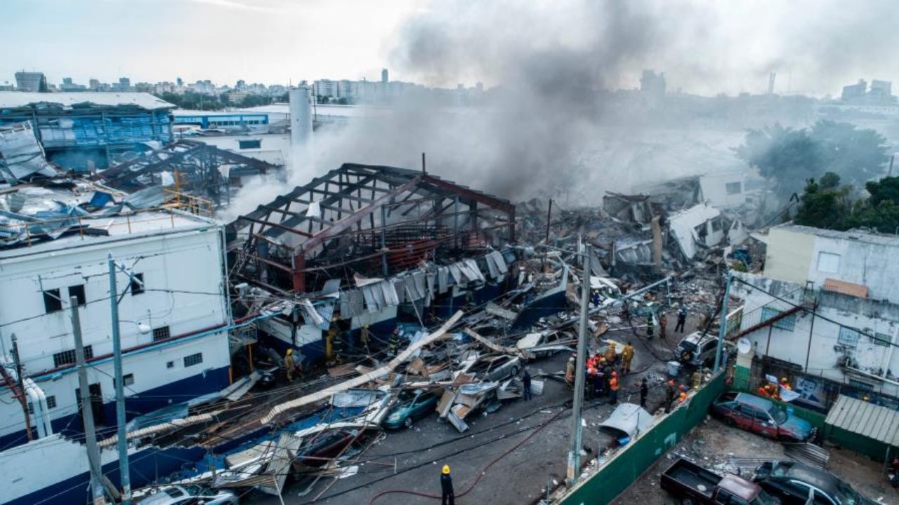 Explosión en fábrica con estructuras colapsadas y humo