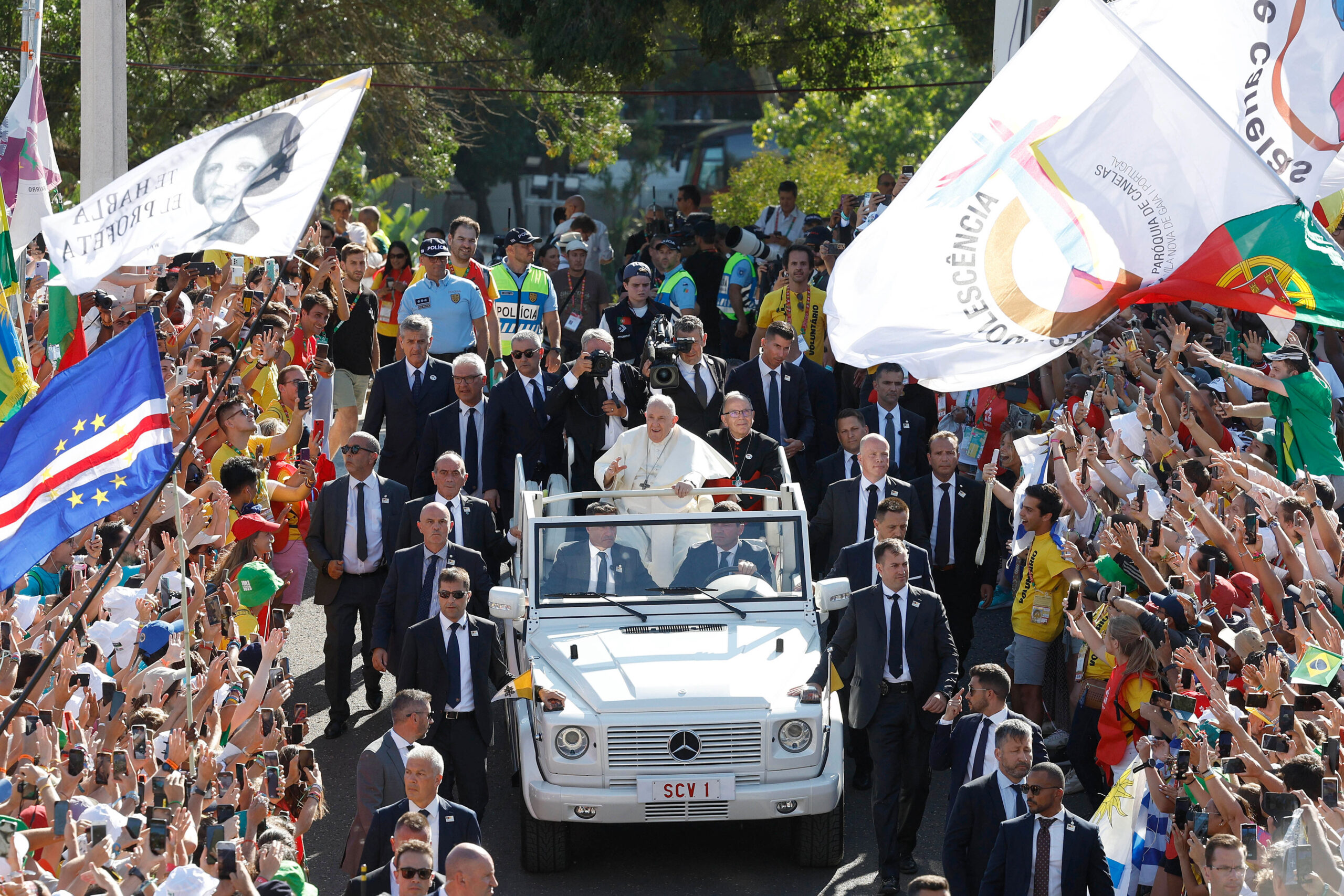 Líder religioso saluda en vehículo a multitud entusiasta.