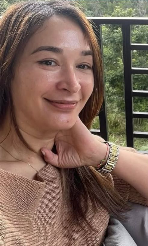 Mujer sonriente en balcón con paisaje verde