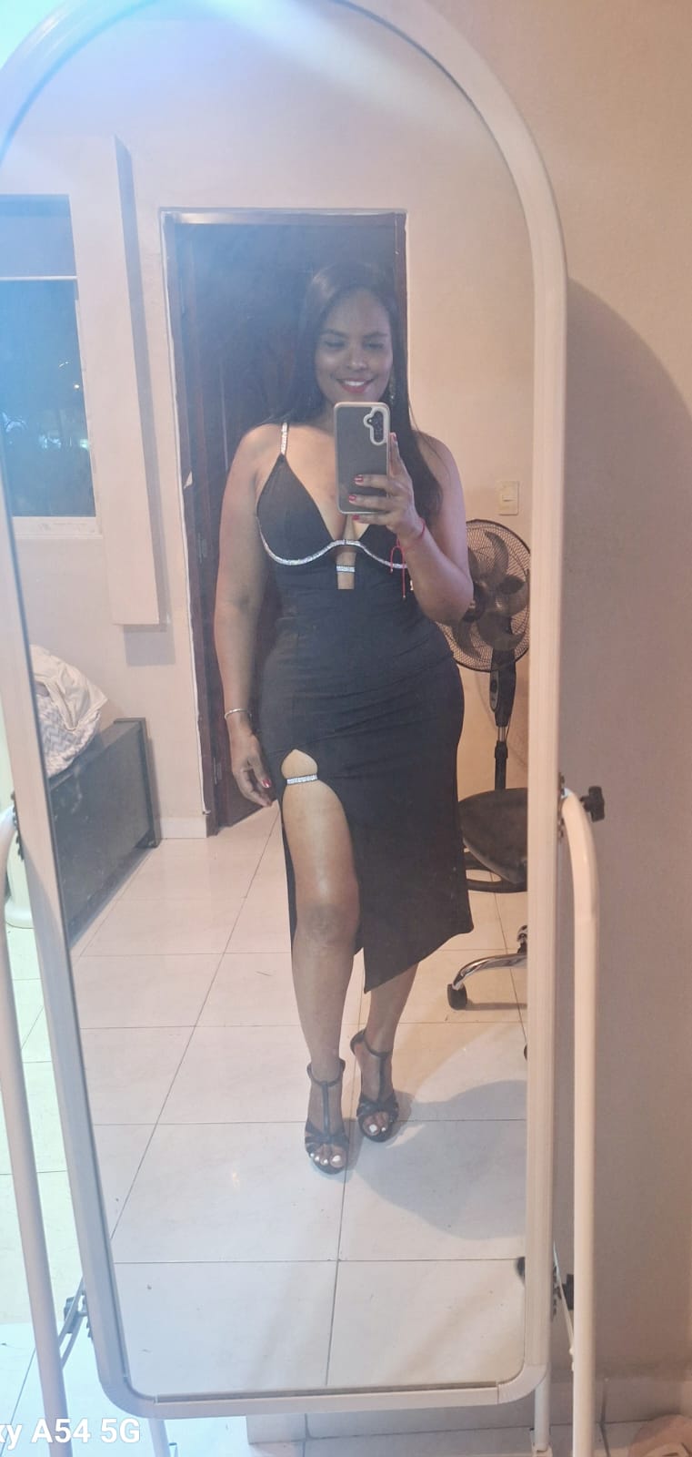 Mujer en vestido negro elegante frente a espejo.