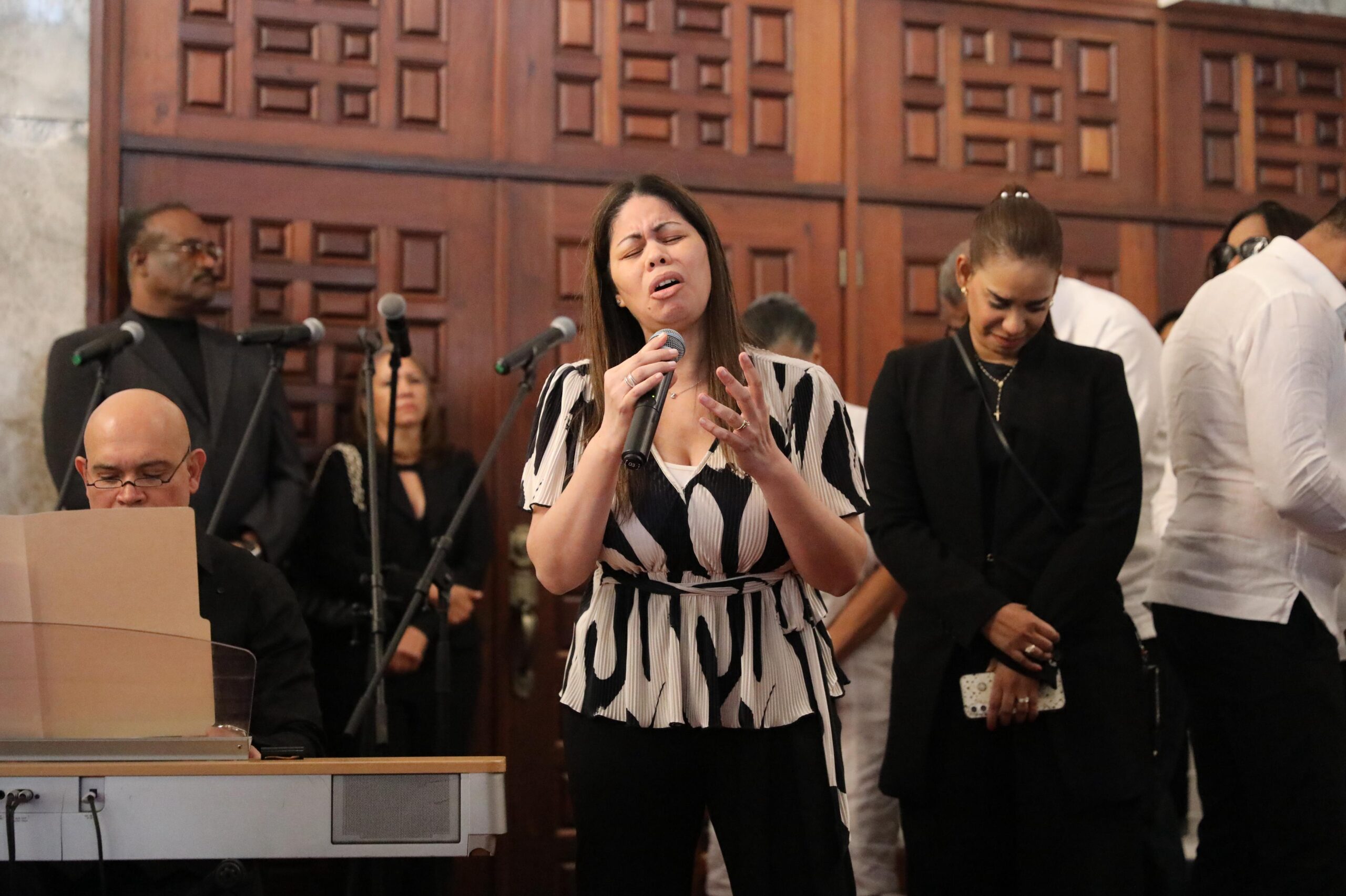 Mujer cantando en evento con micrófono.