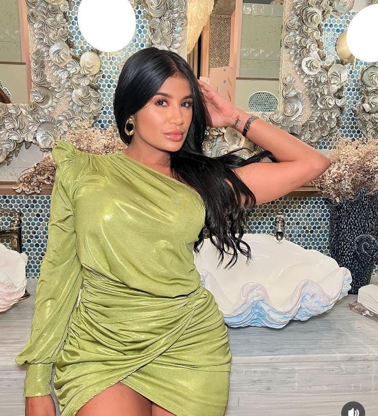 Mujer con vestido verde posando en baño decorado.