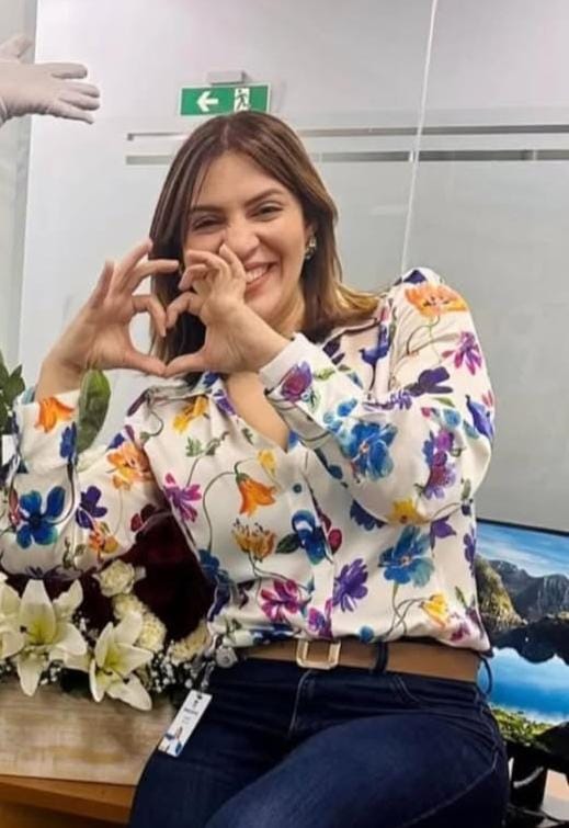 Mujer sonriendo haciendo forma de corazón con manos.