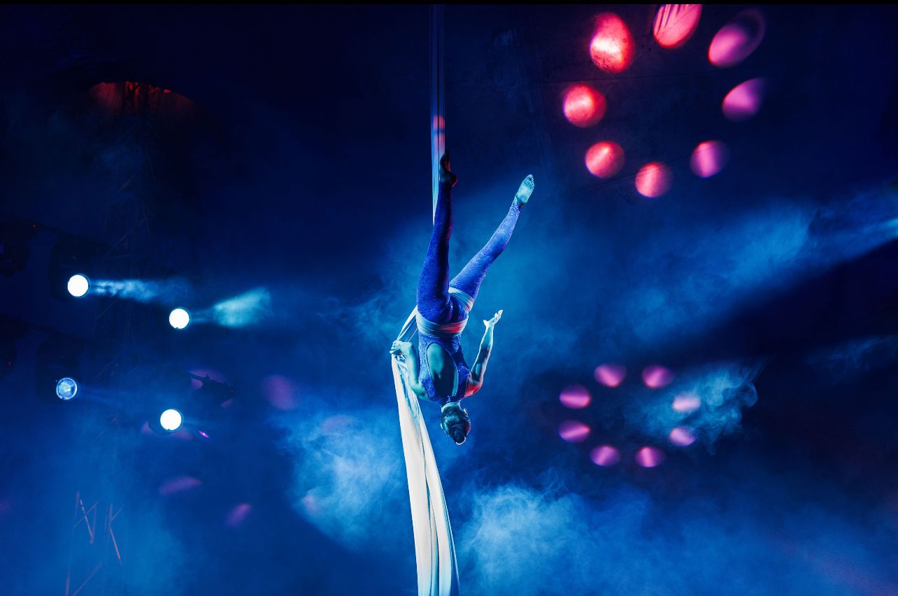 Acróbata suspendido en telas bajo luces azules