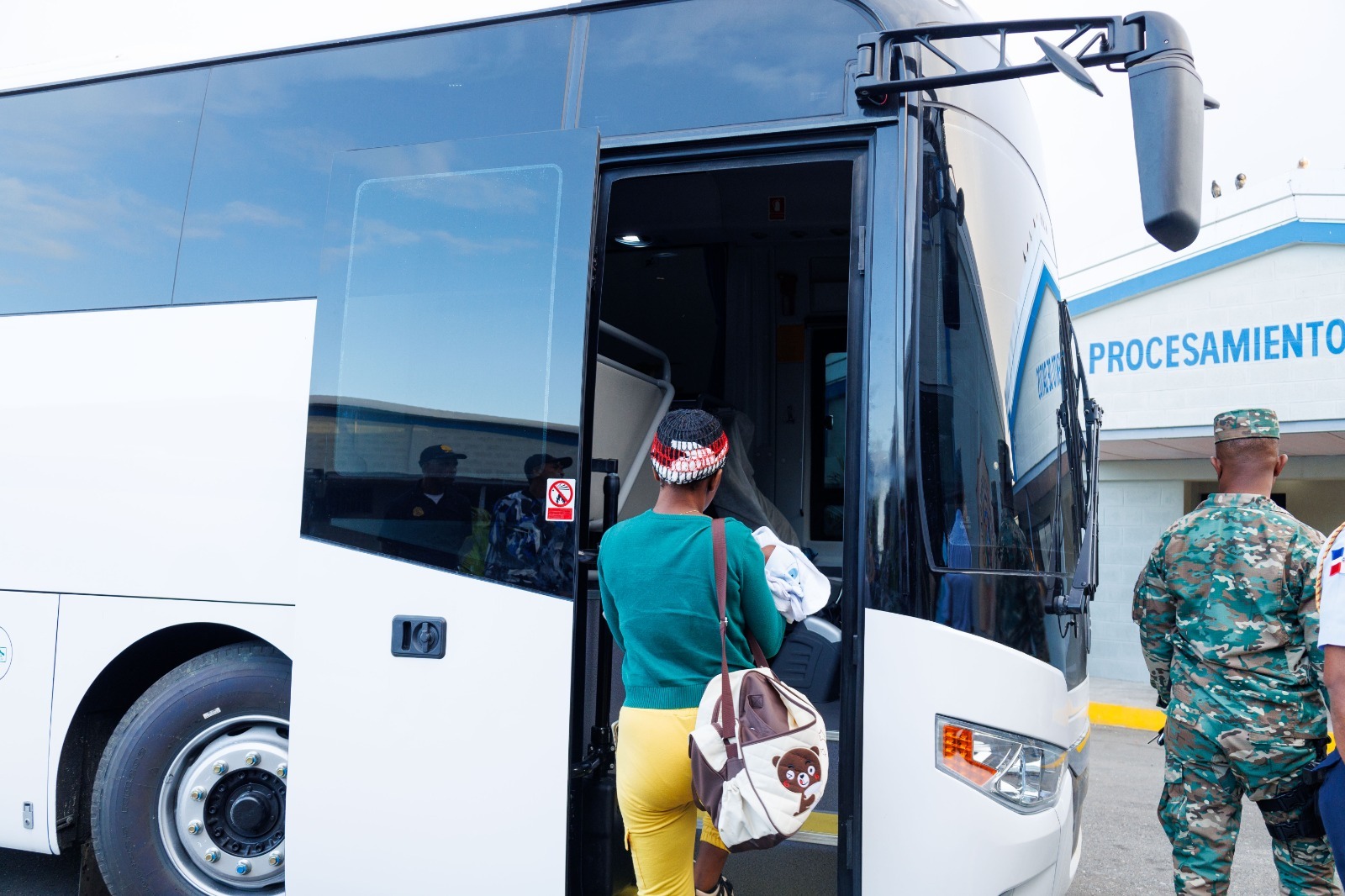 Persona subiendo a un autobús blanco en terminal.