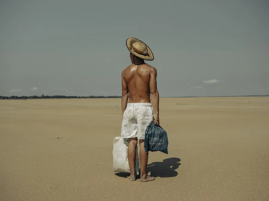 Hombre con sombrero carga bolsas en el desierto.
