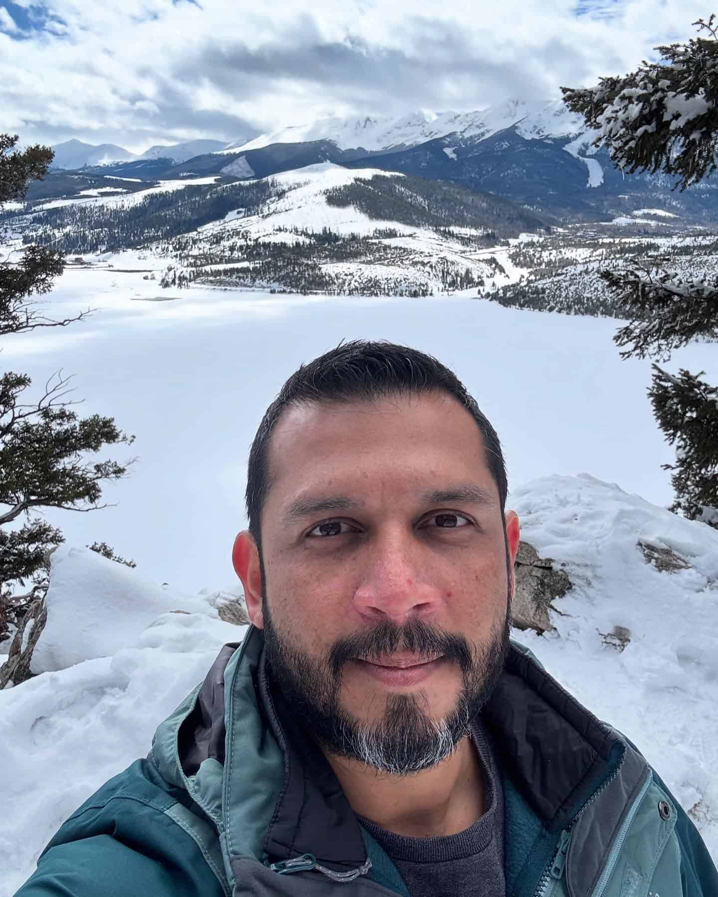 Montañas nevadas con cielo nublado y hombre sonriendo.
