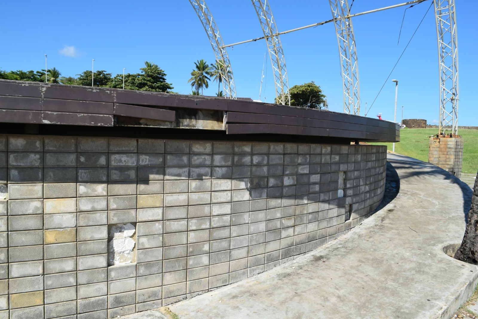 Muro de bloques de concreto, cielo azul, palmeras.