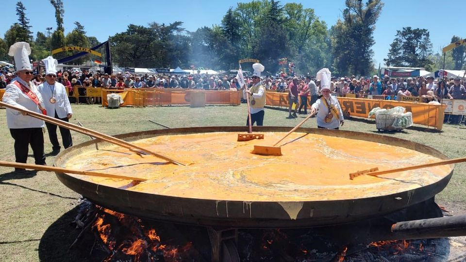 Cocineros preparando gran omelette en festival al aire libre.