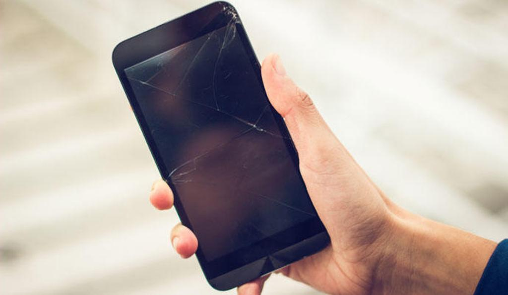 Mano sosteniendo móvil con pantalla rota