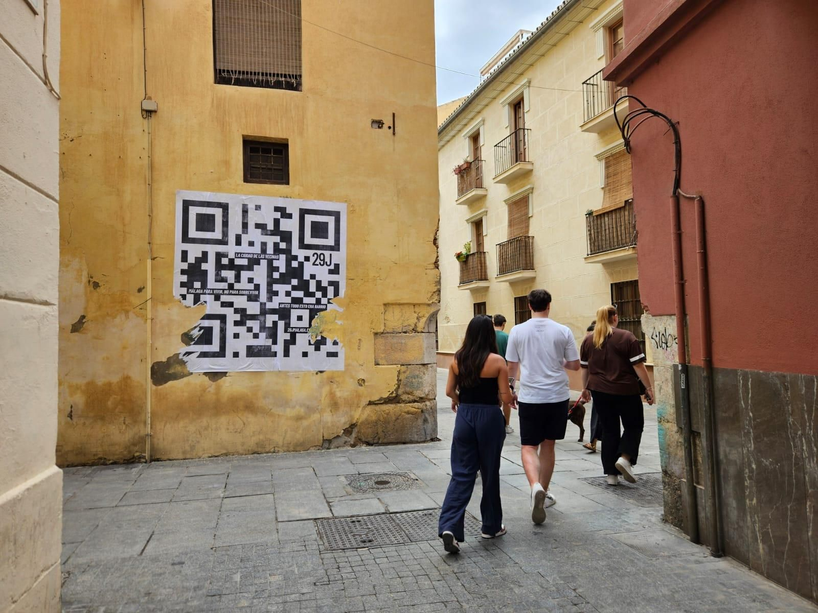 Mural de código QR en calle urbana con personas.