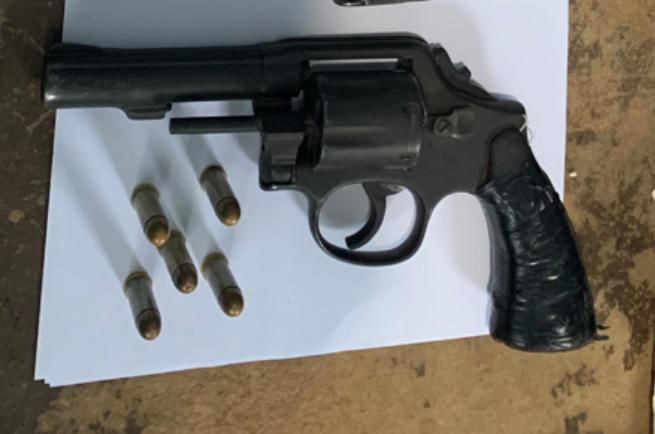 Revólver negro con seis balas en superficie