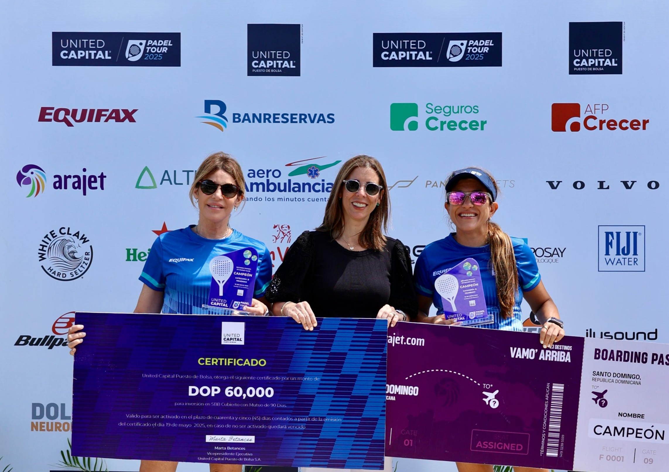 Tres mujeres con premios de torneo de pádel.