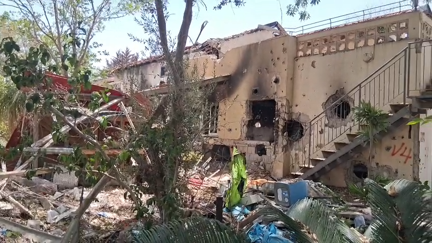 Edificio dañado tras explosión, escombros y vegetación alrededor.