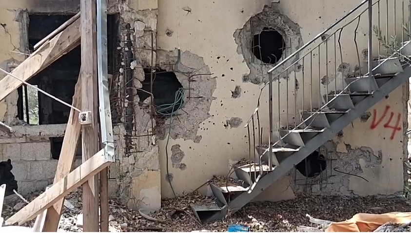 Fachada dañada con escalera metálica y grafiti.