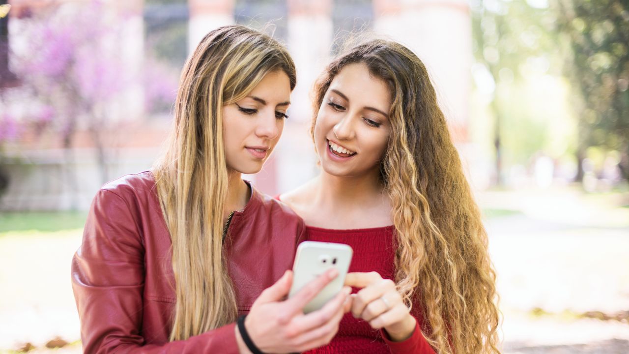 Dos mujeres mirando un móvil en el parque.