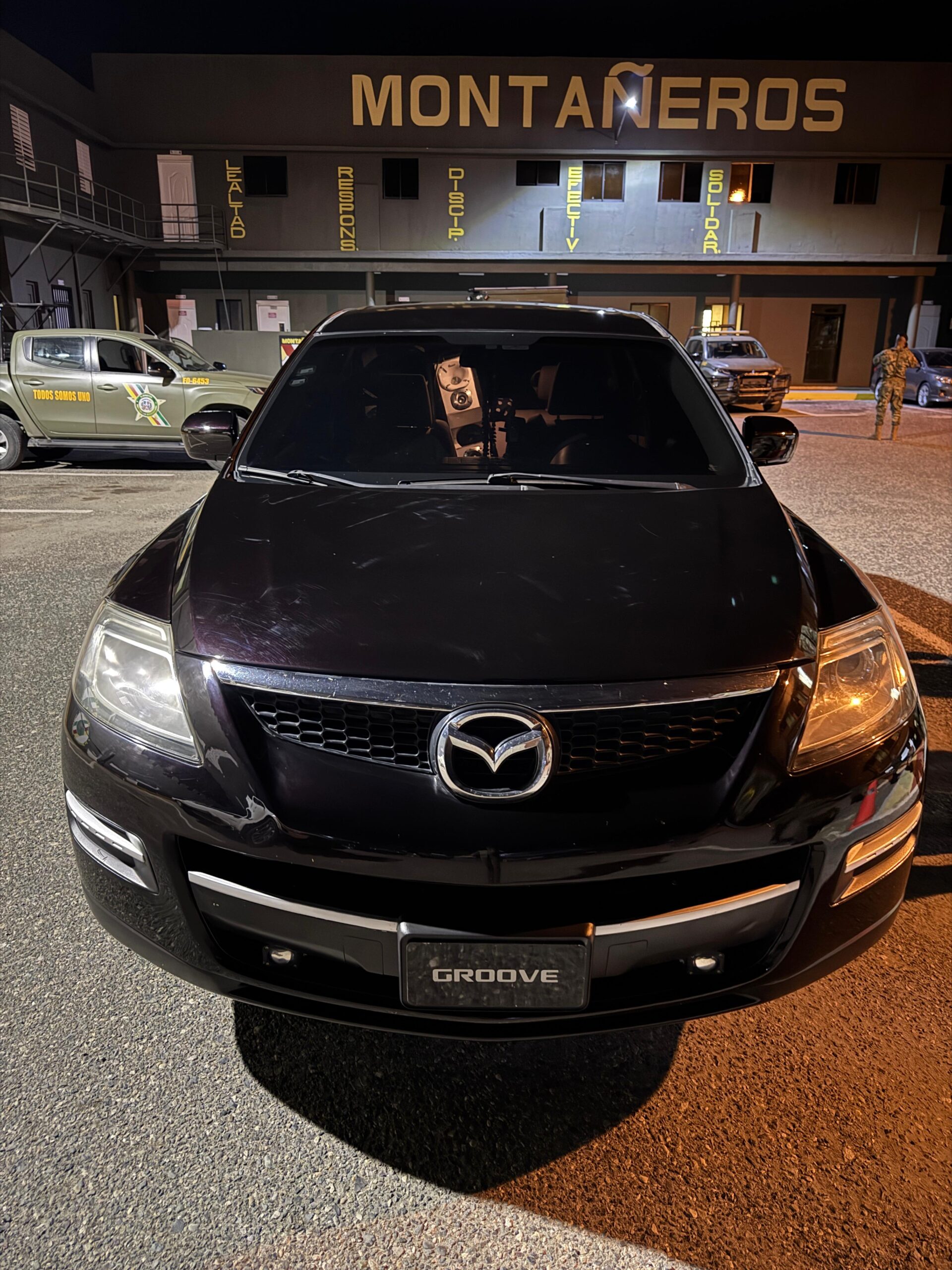 Mazda negro estacionado frente a edificio por la noche
