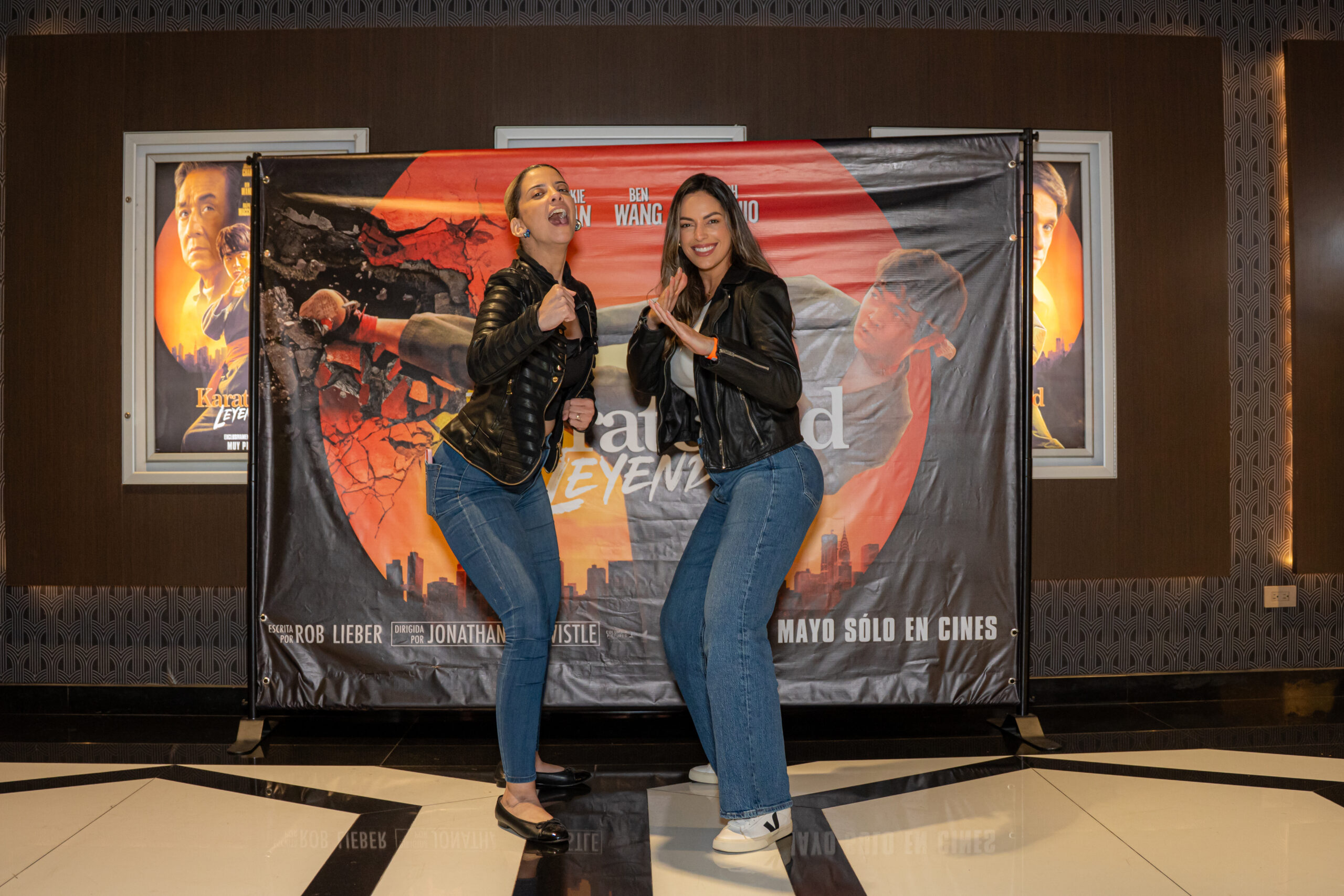 Dos personas posando frente a cartel de película.