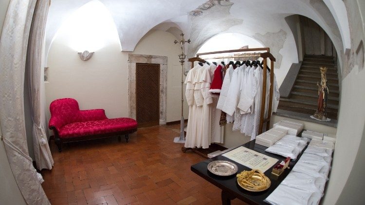 Vestuario religioso en sala antigua con sofá rojo.