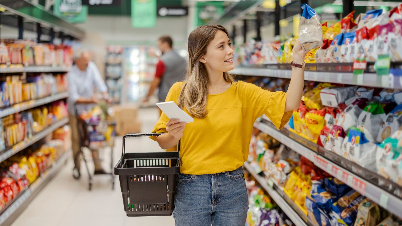 Mujer comprando en supermercado con cesta y lista