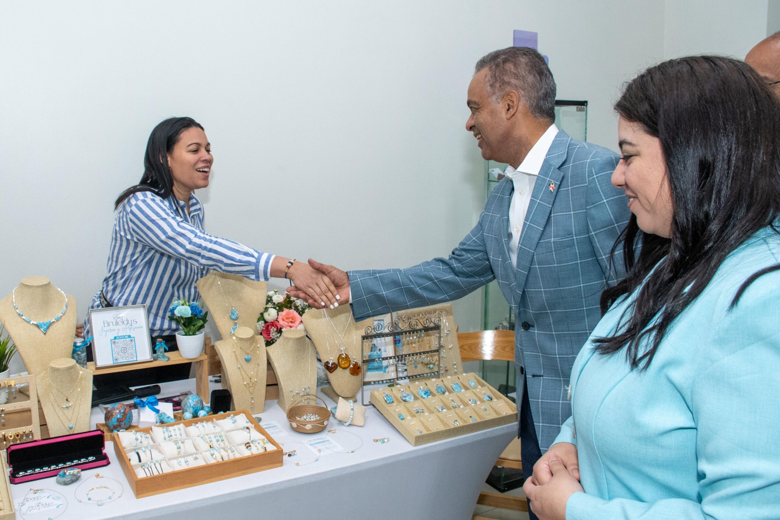 Personas saludando en puesto de joyería artesanal.