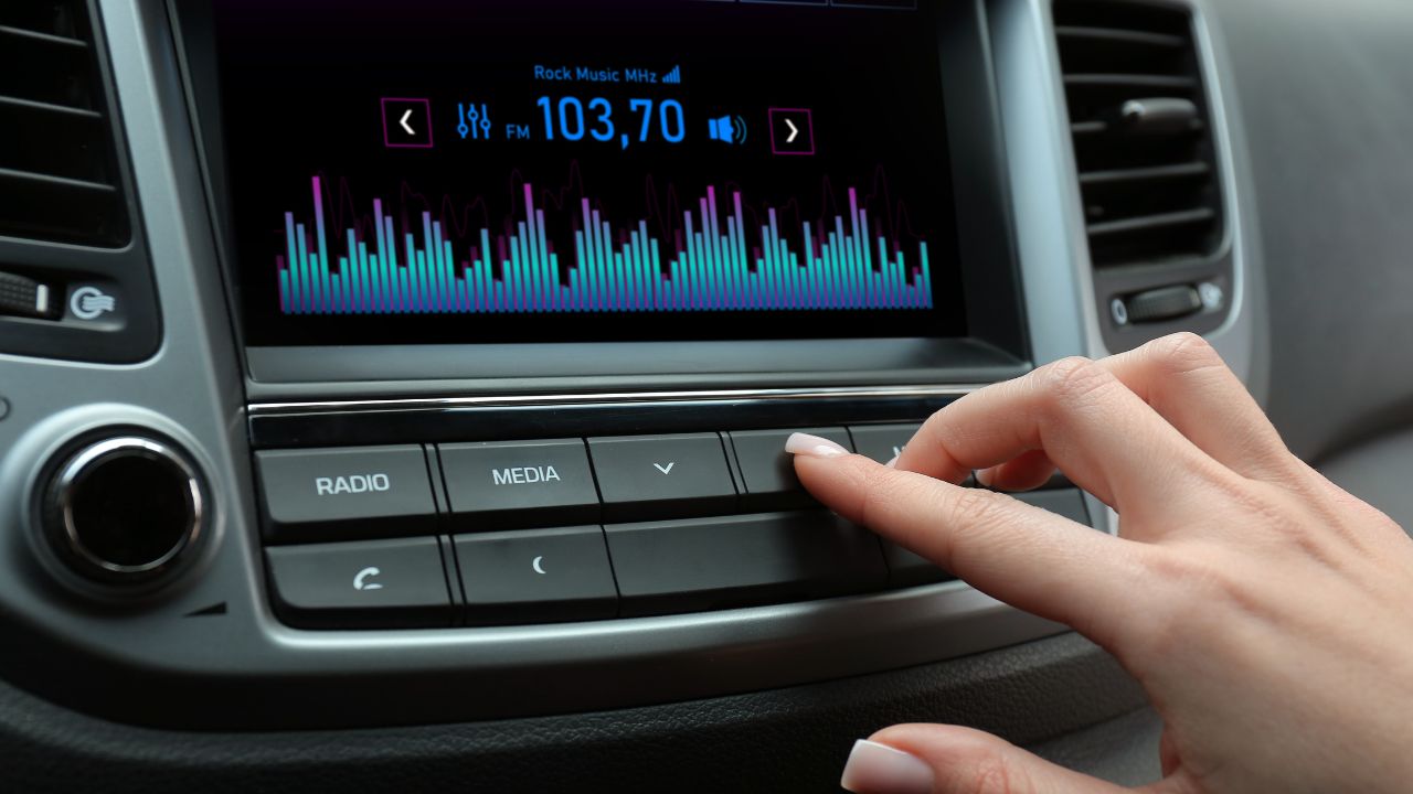 Mujer ajustando radio en coche moderno.