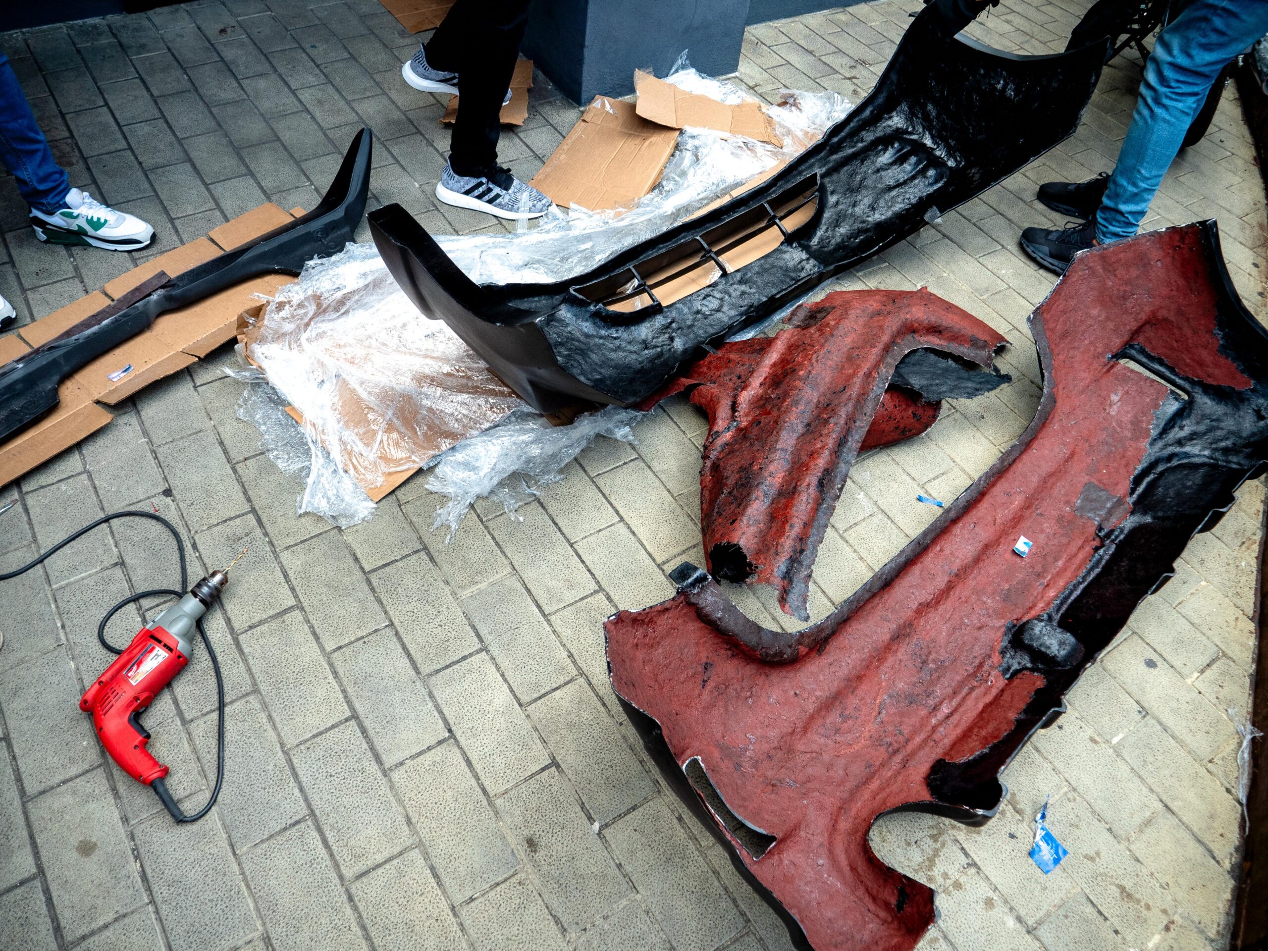 Piezas de coche en el suelo con taladro.