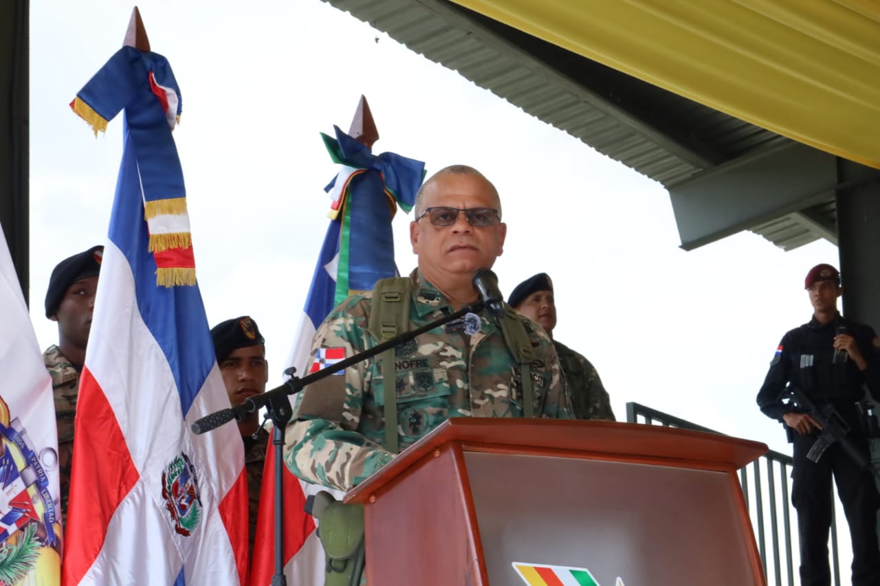 Militar dando discurso con banderas dominicanas