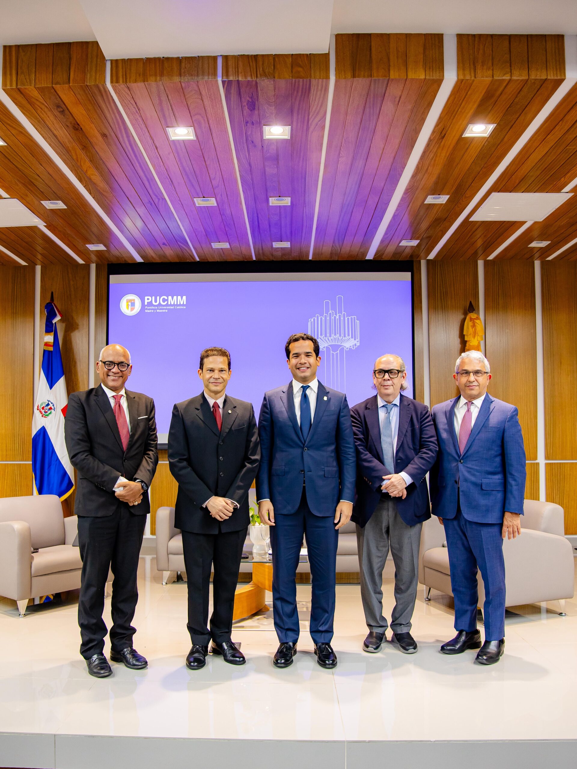 Cinco hombres en trajes en un escenario formal.