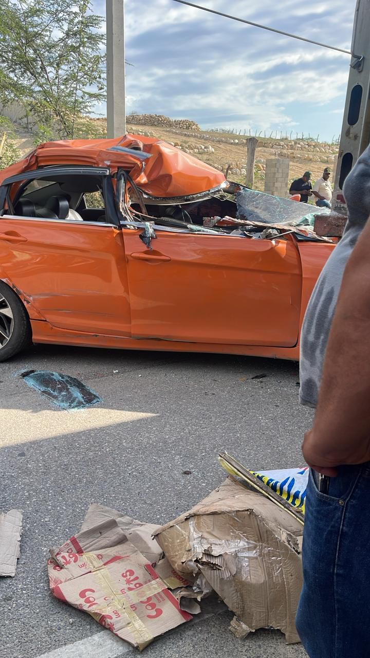 Coche naranja chocado en la carretera, daños visibles.
