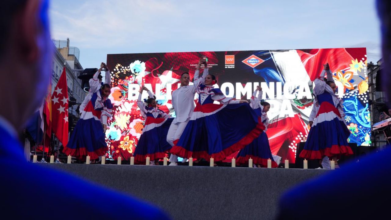 Baile dominicano en escenario con trajes coloridos.