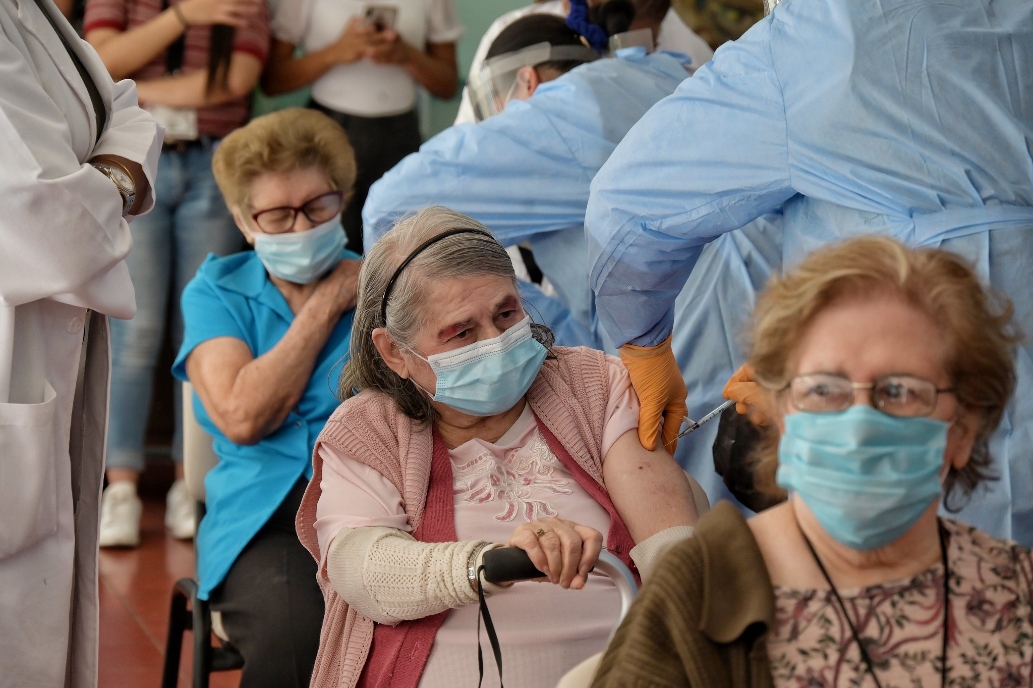 Personas mayores recibiendo vacuna COVID-19, mascarillas puestas.