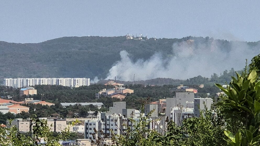 Incendio forestal cerca de edificios y colinas