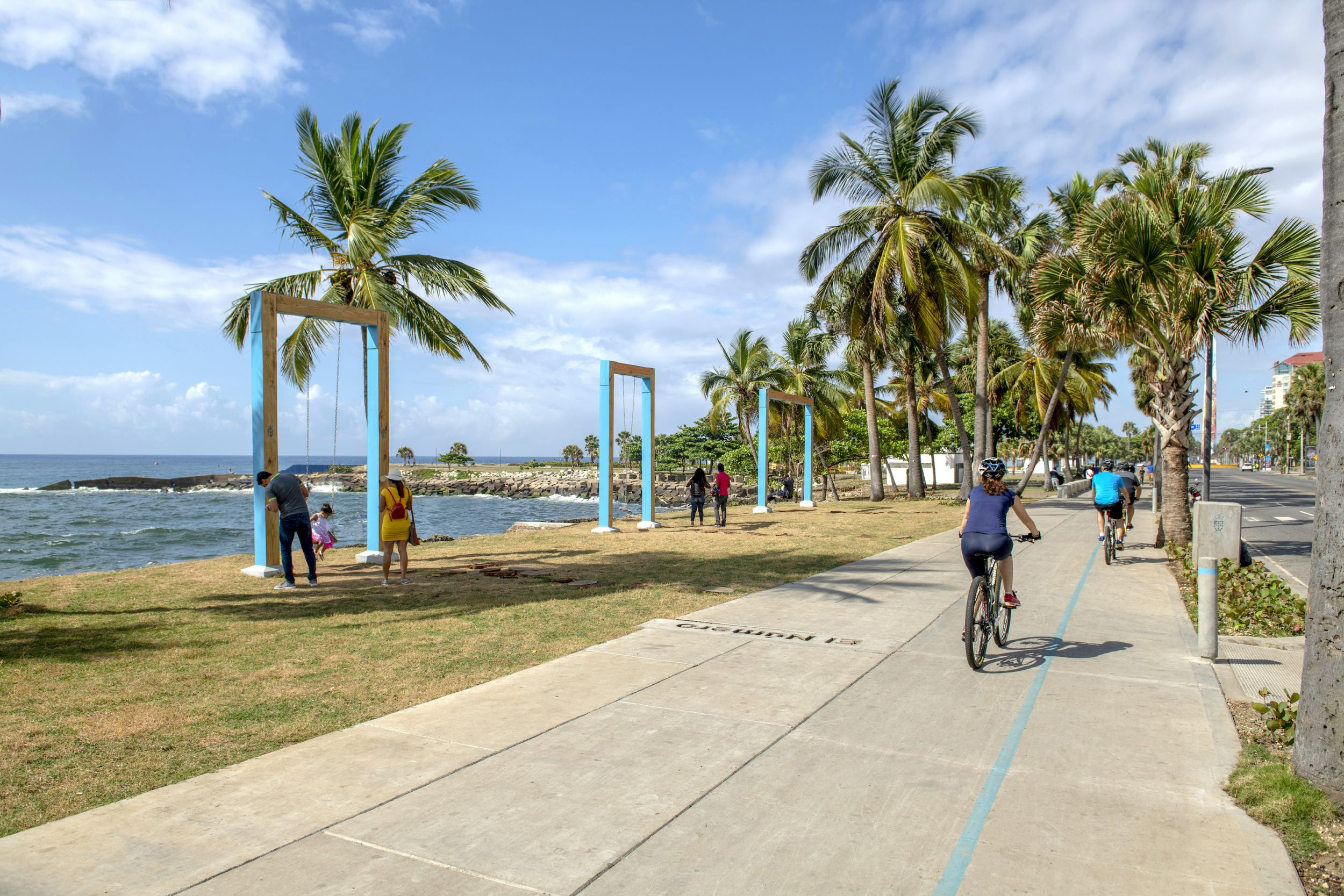 Personas en bici y columpios junto al mar
