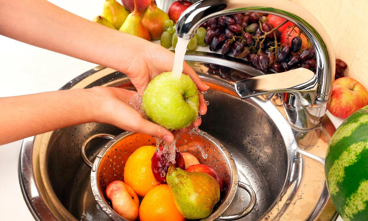 Lavado de frutas bajo el grifo de agua